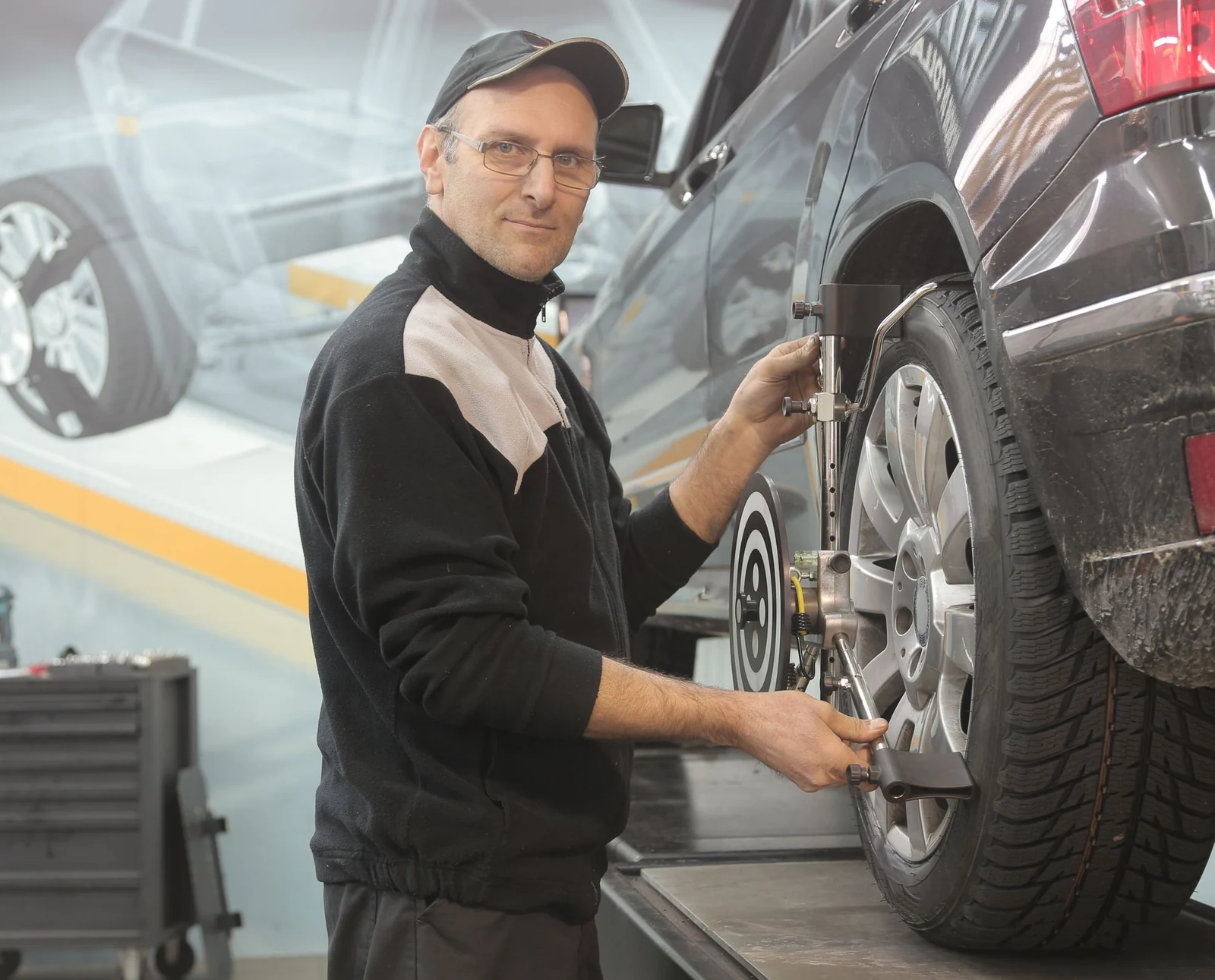 Mechaniker bei der Achsvermessung an einem Auto in der Werkstatt