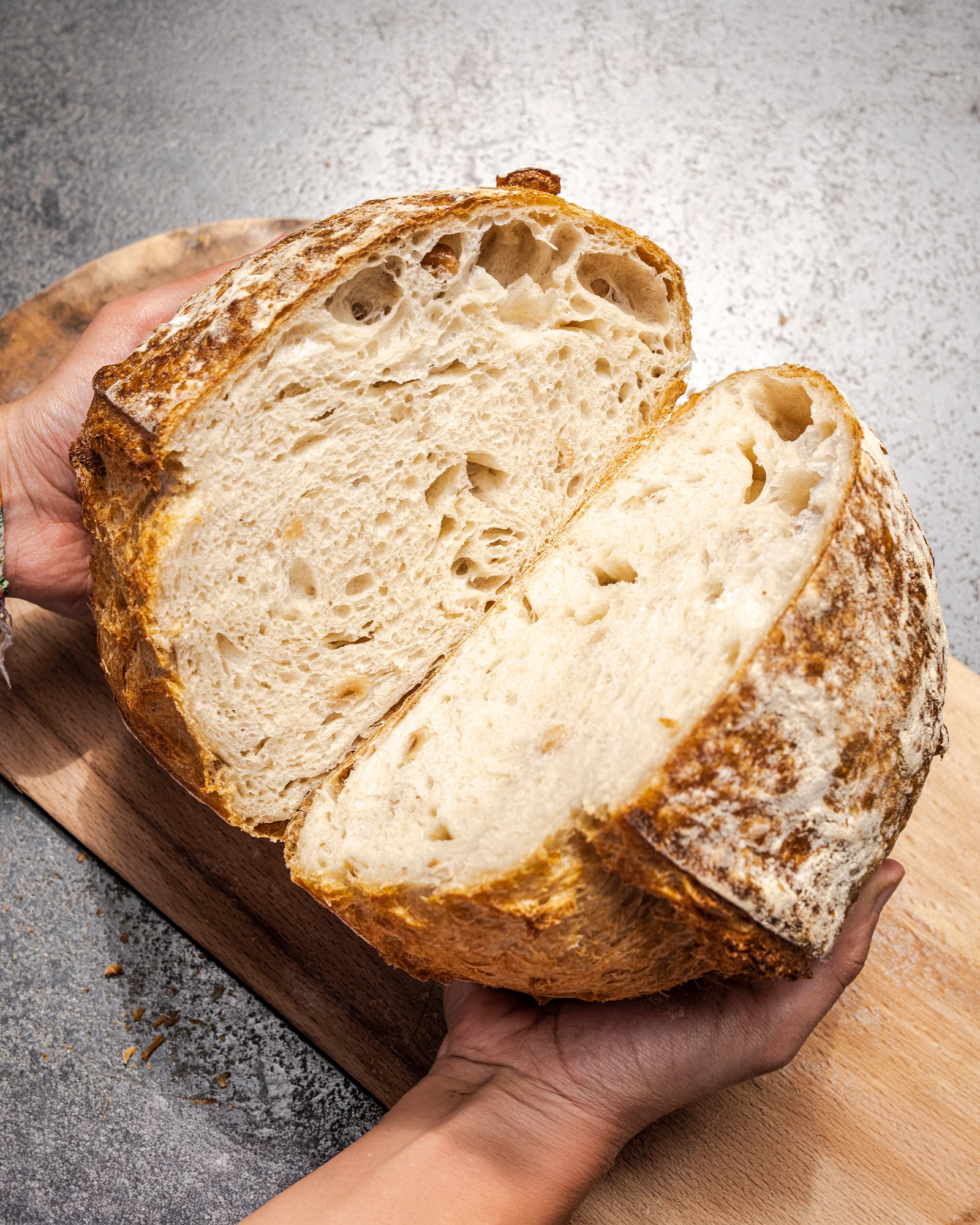 Hände halten ein frisch gebackenes Sauerteigbrot