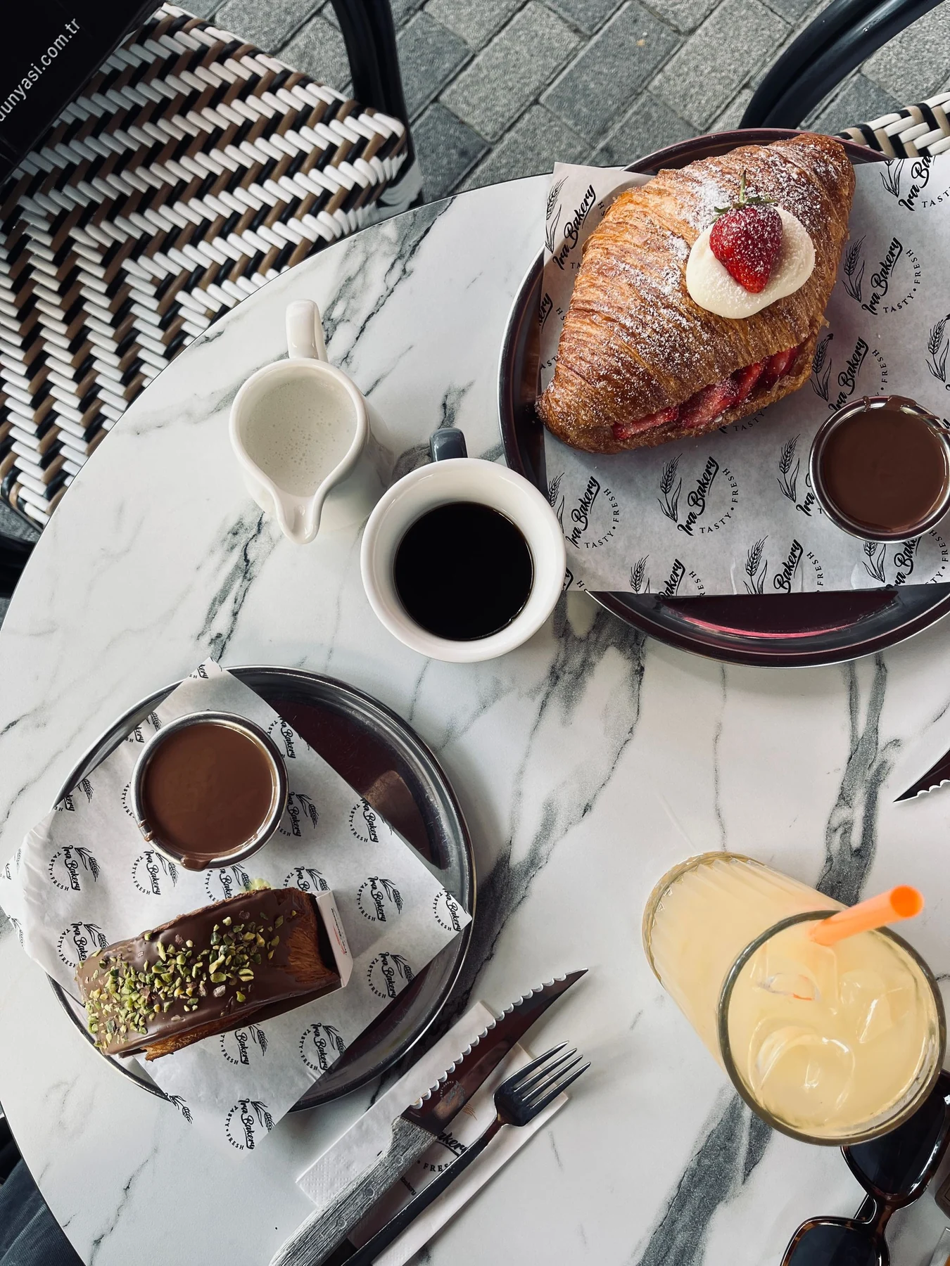 Kaffee und Croissant auf einem gedeckten Café-Tisch