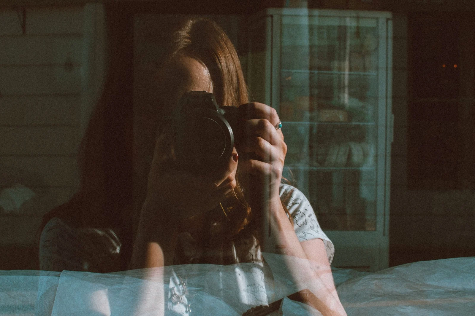 Fotografin mit Kamera vor einer spiegelnden Fensterscheibe