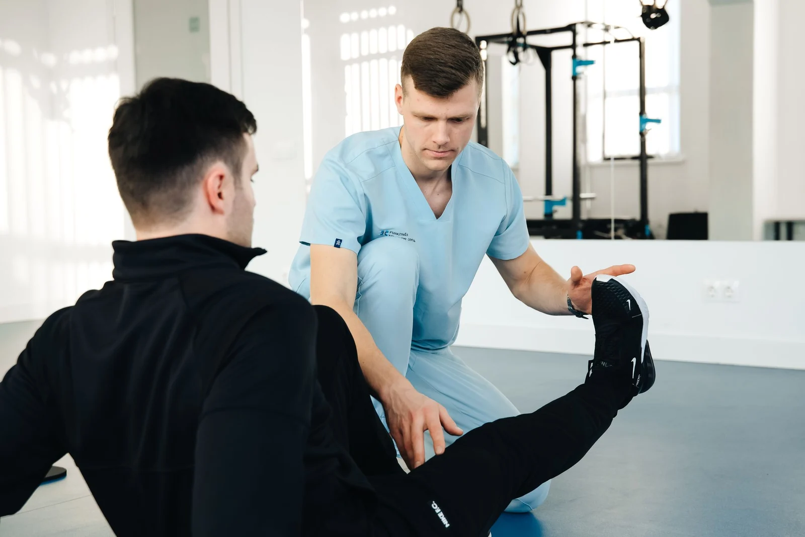 Physiotherapeut begleitet eine Beinübung auf einer Behandlungsliege